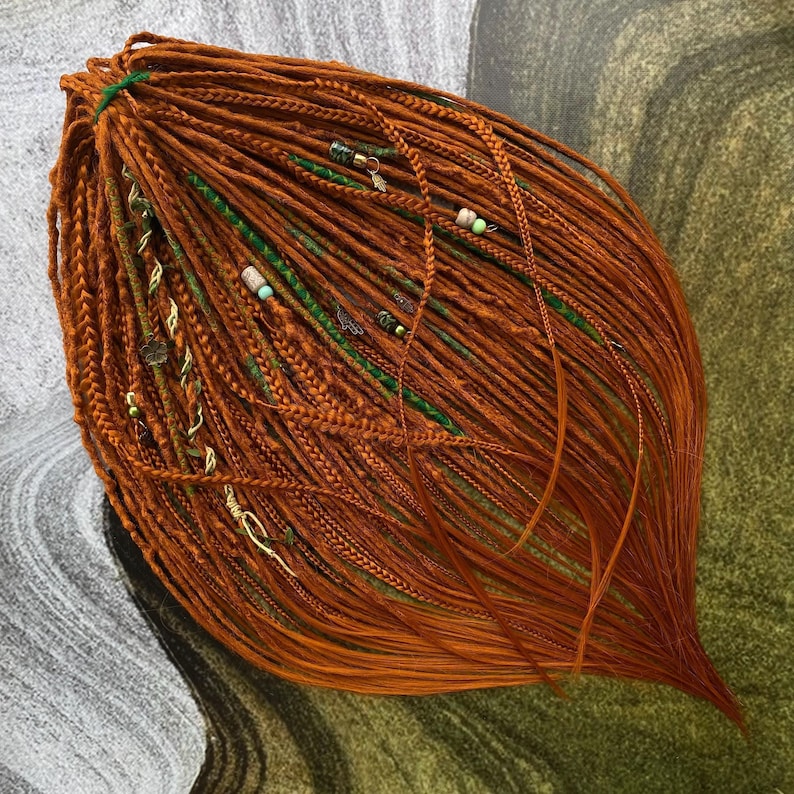 a large, intricate arrangement of braided hair strands in shades of orange and green, creating a visually striking and textured composition.