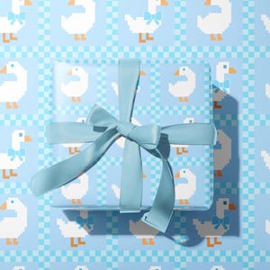 May include: A wrapped gift with a light blue ribbon on a light blue background. The wrapping paper and background feature a repeating pattern of white pixelated geese with blue bows. The gift is centered and the ribbon is tied in a bow.