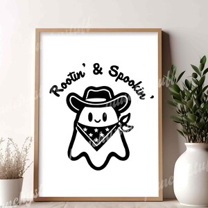 a wood frame with a black and white print of a cowboy ghost that says "Rootin' and Spookin'"