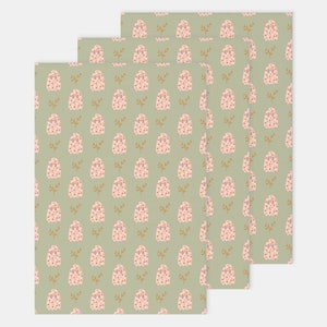 Pode incluir: Tr&ecirc;s folhas de papel de embrulho com um padr&atilde;o repetido de fantasmas rosa e folhas douradas sobre um fundo verde claro.