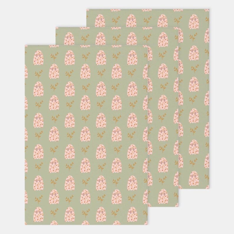 Pode incluir: Tr&ecirc;s folhas de papel de embrulho com um padr&atilde;o repetido de fantasmas rosa e folhas douradas sobre um fundo verde claro.