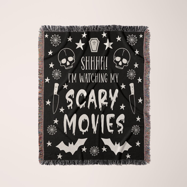 K&ouml;nnte beinhalten: Schwarze und wei&szlig;e gewebte Wurfdecke mit einem gruseligen Halloween-Thema. Sie zeigt Sch&auml;del, Flederm&auml;use, Sterne, Spinnweben und ein Messer. Der Text lautet "Psst! Ich schaue mir meine Horrorfilme an."