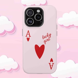 Light pink phone case with red ace of hearts playing card design and 'lucky girl' text written in cute script. Displayed on soft pink background with decorative cloud elements.
