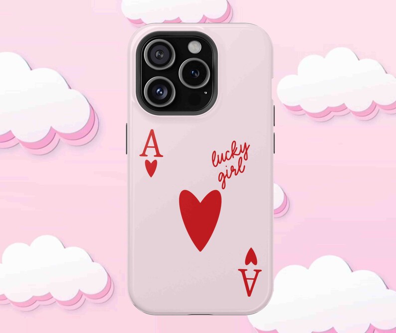 Light pink phone case with red ace of hearts playing card design and 'lucky girl' text written in cute script. Displayed on soft pink background with decorative cloud elements.