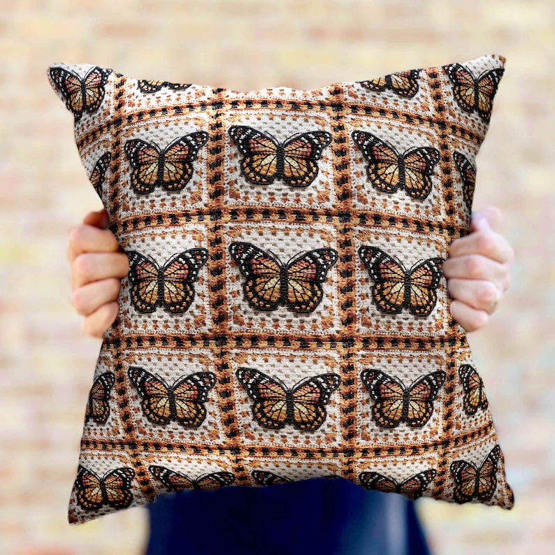 May include: A decorative throw pillow with a pattern of brown butterflies on a white background. The pillow is made of a soft, textured fabric.