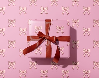 May include: A pink gift box with a red satin ribbon tied in a bow. The box is wrapped in pink paper with a repeating pattern of small white bows.
