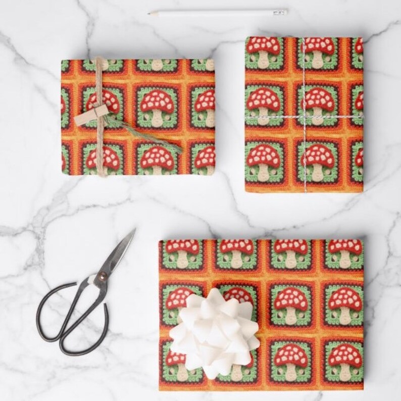 May include: Gift wrap featuring a repeating pattern of red and white mushrooms in green and orange squares. The pattern resembles a crocheted design.