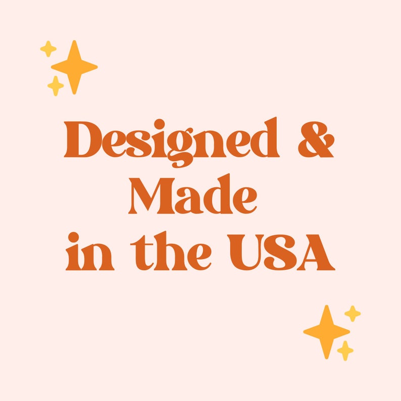 K&ouml;nnte beinhalten: Orangener Text auf rosa Hintergrund lautet "Designed & Made in the USA". Zwei gelbe Sterne mit Glitzer befinden sich auf beiden Seiten des Textes.