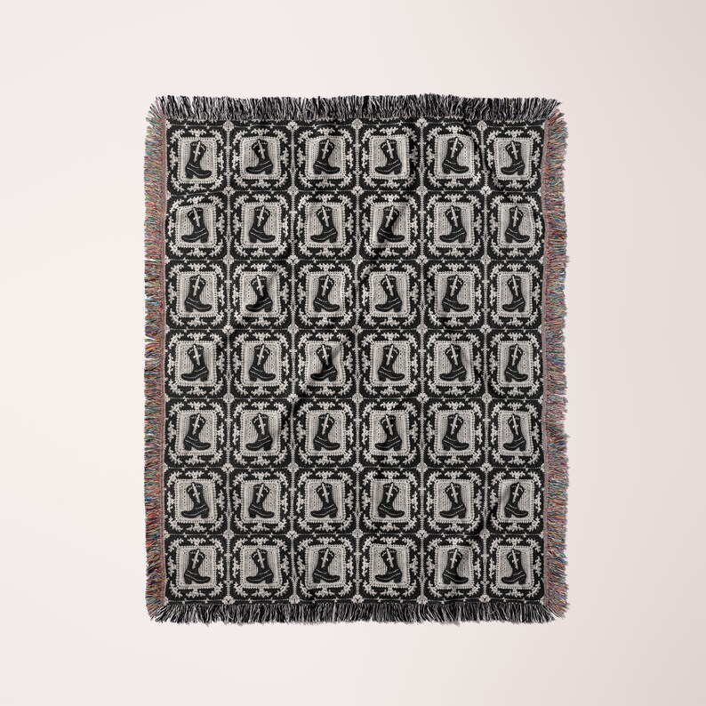 May include: Black and white woven throw blanket with a repeating pattern of cowboy boots in a square frame.