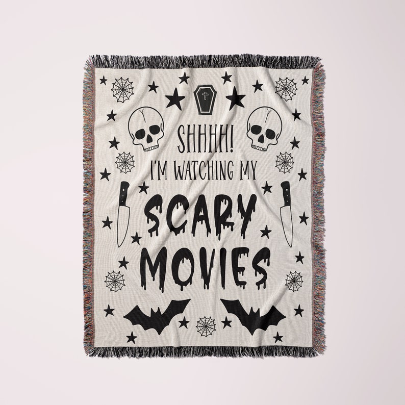 K&ouml;nnte beinhalten: Schwarz-wei&szlig;e gewebte Wolldecke mit einem gruseligen Halloween-Motiv. Sie zeigt einen Sch&auml;del, ein Kreuz, ein Messer, Flederm&auml;use und den Text "Psst! Ich schaue mir meine Horrorfilme an".