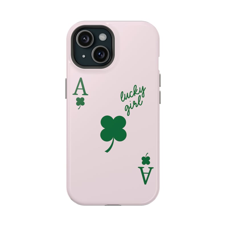 May include: A light pink phone case featuring a green Ace of Clubs card design with a four-leaf clover and the words "lucky girl". The case is designed to fit a smartphone and has a camera cutout.