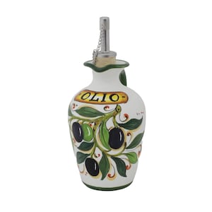 Puede incluir: Botella de aceite de oliva de cerámica blanca con un diseño decorativo de rama de olivo. La botella tiene un pico de metal con una cadena y la palabra "OLIO" en una pancarta amarilla. La botella mide unos 18 cm de alto.