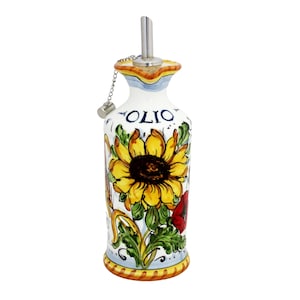 Può includere: Bottiglia per olio d'oliva in ceramica bianca con un motivo a girasole. La bottiglia ha un beccuccio in acciaio inossidabile e una catena attaccata a un tappo. La parola "OLIO" è scritta sulla bottiglia. Decorata con elementi floreali gialli, verdi e rossi.