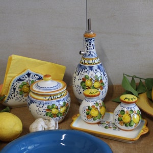 Italian table set, oil cruet, napkinholder, salt and pepper set, garlic jar.The table with a jute tablecloth  is decorated with real lemons and  yellow paper napkin