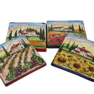 May include: Four square ceramic coasters with hand-painted Italian landscape scenes. Each coaster features a different design: vineyards, sunflowers, poppies, and a Tuscan village. The coasters have colorful borders and are set against a white background.