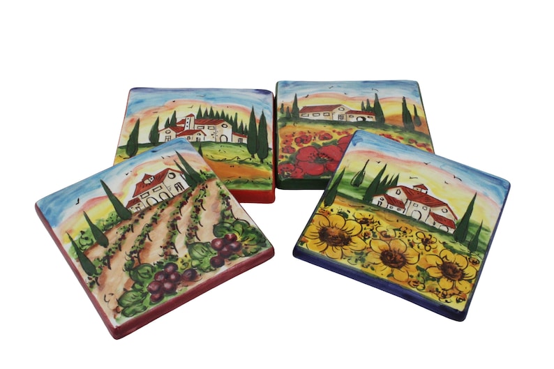 May include: Four square ceramic coasters with hand-painted Italian landscape scenes. Each coaster features a different design: vineyards, sunflowers, poppies, and a Tuscan village. The coasters have colorful borders and are set against a white background.