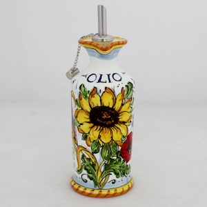 Può includere: Bottiglia di olio d'oliva in ceramica bianca con un design di girasole e papavero rosso. La bottiglia ha un beccuccio di versamento in metallo e un tappo di sughero. La parola "OLIO" è scritta sulla bottiglia.