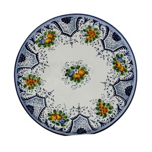 Può includere: Un piatto rotondo in ceramica bianca con bordo blu e intricati disegni floreali. Il piatto presenta grappoli di frutta gialla e verde con accenti blu, circondati da motivi blu ornati. Il diametro del piatto è di circa 30 cm.