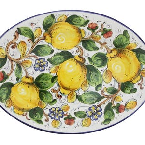 May include: Oval ceramic serving platter with a hand-painted lemon design. The white platter features yellow lemons, green leaves, and brown vines, with a blue rim. The design includes small blue and red floral accents.