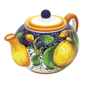 Può includere: Teiera in ceramica con un motivo a limoni su sfondo blu. La teiera ha un beccuccio e un manico gialli, un coperchio bianco con bordo giallo e un pomello blu. Il motivo a limoni include limoni gialli e foglie verdi.
