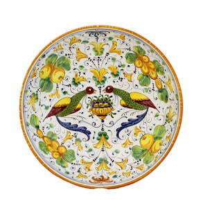 Puede incluir: Un cuenco de cerámica blanca con un diseño floral colorido que presenta dos pájaros, limones amarillos y hojas verdes. El cuenco tiene un borde amarillo y un patrón floral azul y blanco.