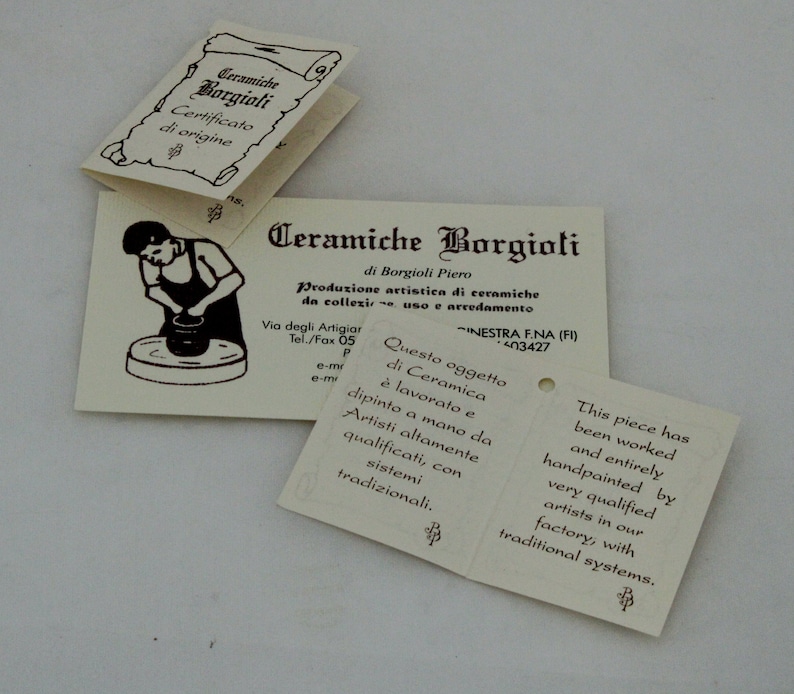 May include: Off-white paper tags with text in Italian and English. The tags feature the words "Ceramiche Borgioli" and include illustrations of pottery being made. The tags describe the ceramic pieces as hand-painted.