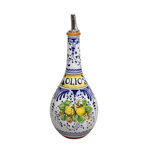 May include: A ceramic olive oil bottle with a decorative design. The bottle is white with blue and yellow accents, and features a floral and fruit motif. The word "OLIO" is printed on the bottle. It has a metal spout with a chain.