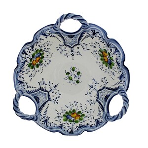 K&ouml;nnte beinhalten: Wei&szlig;es Keramik-Serviertablett mit gewelltem Rand und drei gedrehten Griffen. Das Tablett hat einen blauen Rand und aufwendige Blumen- und Rankenmuster in Blau, Gr&uuml;n und Gelb. Ein dekoratives St&uuml;ck zum Servieren von Speisen.