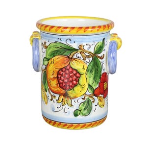 May include: A ceramic vase with a hand-painted pomegranate design. The vase features a white base with a yellow rim and blue handles. The pomegranate is depicted in shades of red, yellow, and orange, with green leaves and a red flower.