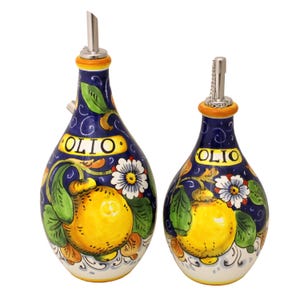 Può includere: Due bottiglie per olio in ceramica con beccucci in acciaio inossidabile. Le bottiglie sono blu scuro con testo giallo che recita "OLIO" e presentano un disegno di limoni gialli, foglie verdi e fiori bianchi. Decorative e adatte per la cucina.