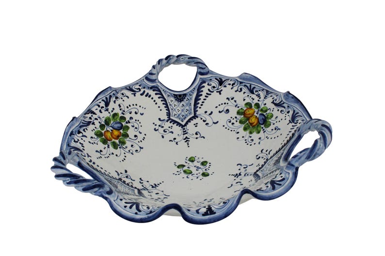 K&ouml;nnte beinhalten: Wei&szlig;es Keramik-Serviertablett mit blauen Verzierungen und Griffen. Das Tablett hat ein Blumendesign mit gr&uuml;nen, gelben und blauen Akzenten. Die Griffe haben ein gedrehtes Seil-Design.
