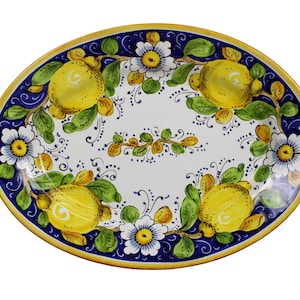 May include: Oval ceramic serving platter with a hand-painted design. The platter features a white centre with yellow lemons, green leaves, and white flowers. The rim is blue with a yellow border. A decorative piece for serving food.