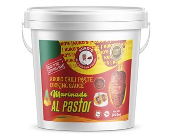 May include: A white plastic bucket with a red, yellow, and green label. The label says "Adobo Chili Paste Cooking Sauce Marinade Al Pastor" and "Kuko's Michoacan Foods". The bucket contains 20 pounds of marinade.