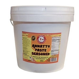 May include: A white plastic bucket with a yellow and red label. The label says "Kuko's Michoacan Foods Annatto Paste Seasoned Pasta de Achiote Sazonado Net wt. 20lbs".