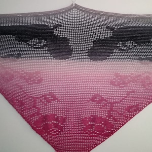 May include: A triangular crocheted shawl with a gradient of colors from black to pink. The shawl has a delicate lace pattern with floral motifs.