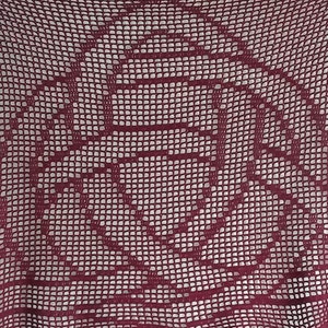 May include: A close-up of a maroon crocheted fabric with a floral pattern.