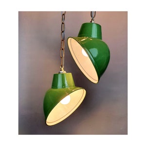 May include: Two green pendant lights with white interiors and chains hanging from the ceiling.