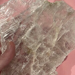 May include: A large, clear, translucent piece of selenite crystal with a layered, flaky texture. The crystal is irregularly shaped and has a slightly rough surface.