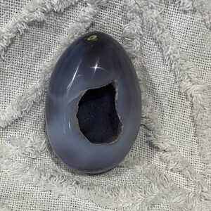 May include: A light purple agate crystal egg with a large, dark purple, hollowed-out center.