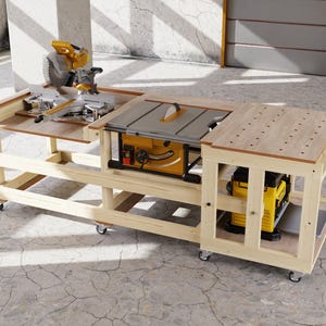 May include: A light-colored wooden workbench on casters featuring a miter saw on the left, a table saw in the center, and a perforated work surface on the right, with a yellow and black planer stored on the lower shelf of the right section.
