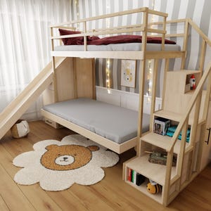 May include: A light wood bunk bed with a slide and stairs. The top bunk has a burgundy comforter and pillow. The bottom bunk has a gray mattress. A bear-shaped rug is on the floor.