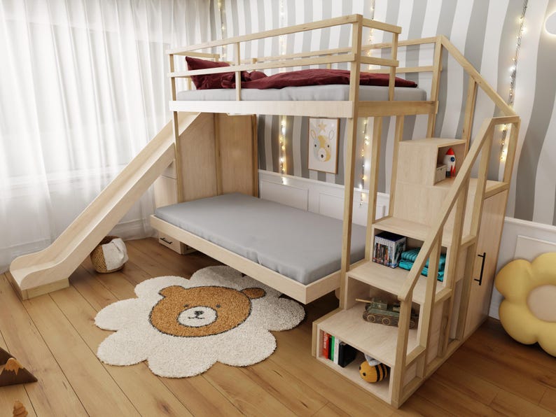 May include: A light wood bunk bed with a slide and stairs. The top bunk has a burgundy comforter and pillow. The bottom bunk has a gray mattress. A bear-shaped rug is on the floor.