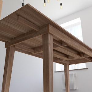 May include: A wooden dining table with a rectangular top and four legs. The table is made of light brown wood and has a simple, modern design.