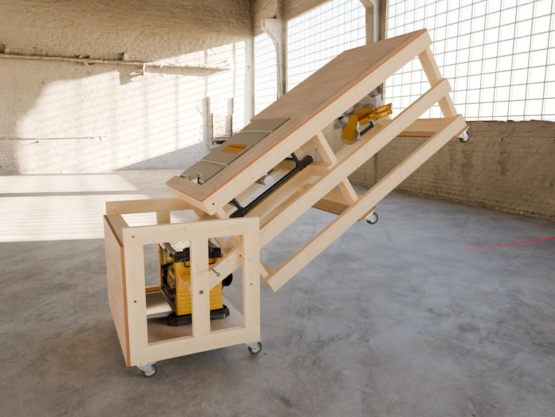 May include: A light-colored wooden workbench on casters featuring a hinged, tilting top surface. A yellow and black power tool is mounted within the lower frame, while a second yellow and black power tool is attached to the underside of the tilting top.