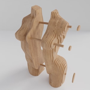 May include: A wooden sculpture made of layered pieces of wood. The sculpture is abstract and has a unique, organic shape. The sculpture is assembled with wooden dowels.