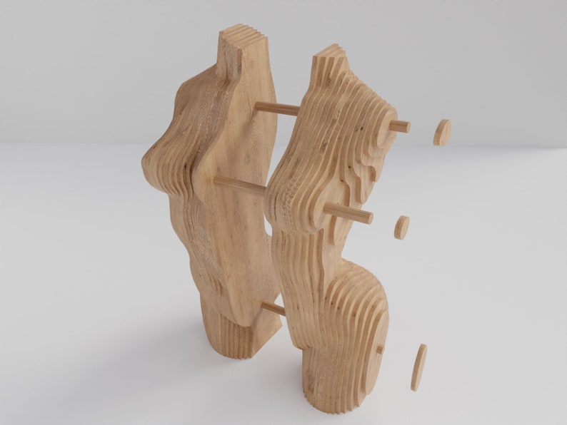 May include: A wooden sculpture made of layered pieces of wood. The sculpture is abstract and has a unique, organic shape. The sculpture is assembled with wooden dowels.