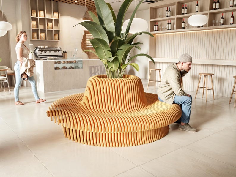 May include: A large, wooden, curved bench with a unique design. The bench is made of light brown wood and has a series of curved slats that create a wave-like effect. The bench is in a modern cafe setting with a plant in the center.