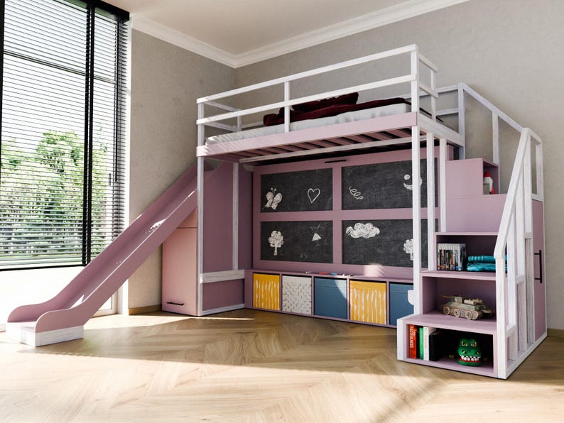 May include: A pink and white loft bed with a slide and stairs. The bed has a chalkboard wall with drawings, storage cubes, and shelves with toys and books. The bed is in a room with a large window.