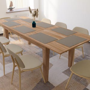 May include: A wooden dining table with six chairs and gray placemats. The table is set with a vase of flowers in the center.