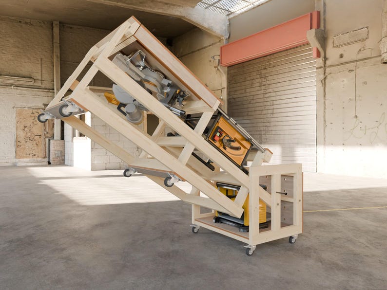 May include: A mobile wooden workbench featuring a hinged, tilting frame mounted on casters. The structure supports a yellow and black table saw and a miter saw, with a yellow and black planer stored on the lower shelf within the wooden base frame.